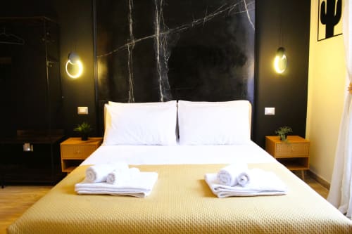 Camera da letto moderna a Blackwoody Contemporary Hospitality a Napoli con cuscini bianchi, coperta gialla, lampade a sospensione e