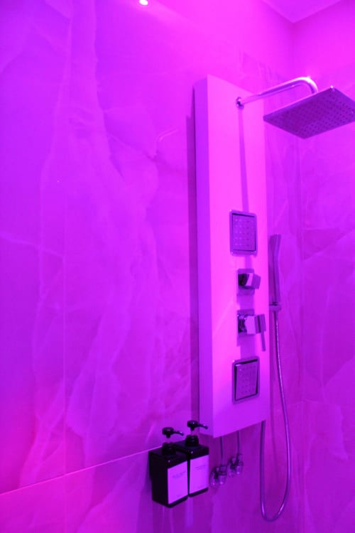 Area doccia moderna con illuminazione neon rosa nella BCH Toledo Room di Blackwoody Contemporary Hospitality, Napoli