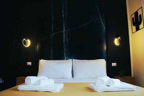 Camera moderna a Blackwoody Contemporary Hospitality a Napoli con testata in marmo nero, luci a forma di luna e bianco
