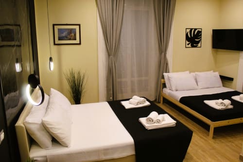 Camera da letto moderna con due letti presso Blackwoody Contemporary Hospitality a Napoli, con pareti gialle, pavimenti in legno e arredamento minimalista
