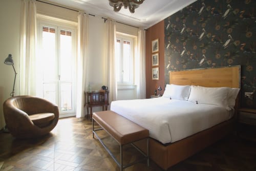 Camera Doppia Superiore a Porta Tosa Milano con letto in legno, vista sulla città, poltrona e elegante carta da parati scura