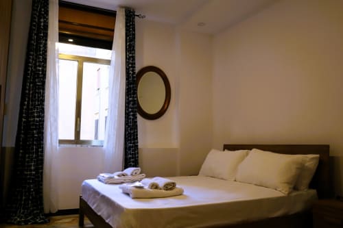 Bright bedroom at Blackwoody Contemporary Hospitality B&B in Naples with queen bed, rolled towels, round mirror, and window