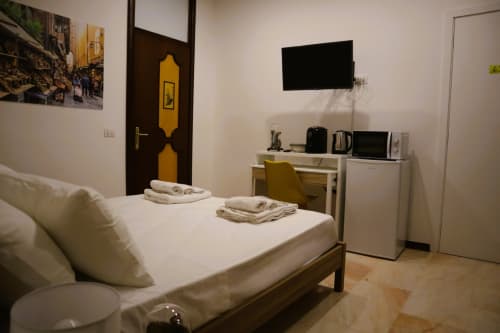 Modern bedroom at Blackwoody Contemporary Hospitality B&B in Naples with bed, desk, TV, and yellow-accented door