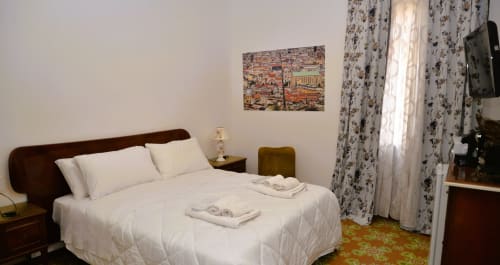 Blackwoody Contemporary Hospitality bedroom in Naples with double bed, white linens, wooden headboard, floral curtains, and