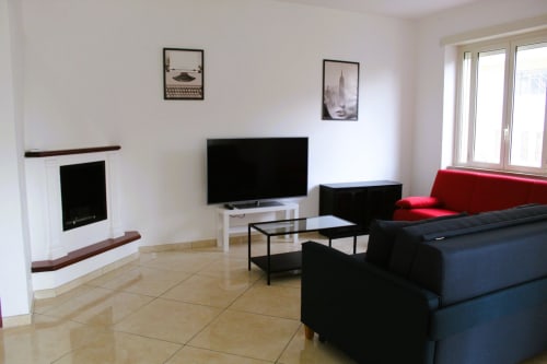 Modern living room at Blackwoody B&B Naples with fireplace, flat-screen TV, red accent sofa, and contemporary furnishings
