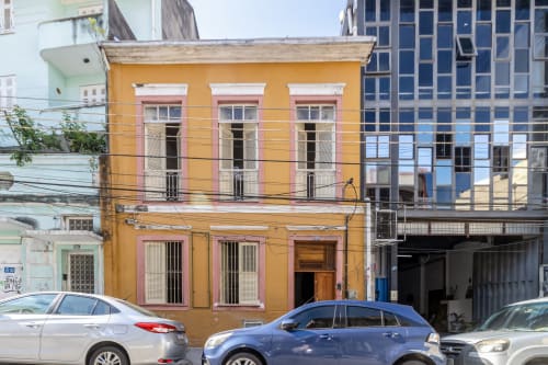 Hostel Rio Vibes: edifício colonial amarelo vibrante no Rio de Janeiro com janelas orladas de rosa e carros estacionados