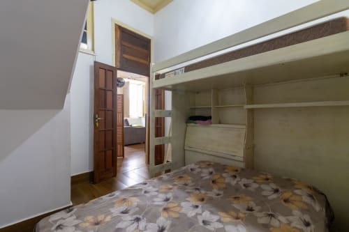 Quarto Triple Suite no Rio Vibes Hostel no Rio de Janeiro com cama suspensa, piso de azulejo, guarda-roupa e porta de madeira