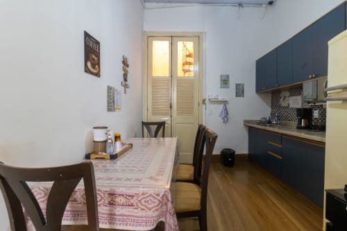 Cozinha-sala de jantar da Suite Tripla Rio Vibes Hostel com mesa, cadeiras, móveis escuros e portas para o pátio