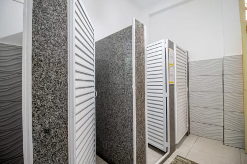Cabines de banheiro com divisórias em granito e textura ondulada no Rio Vibes Hostel, dormitório misto no Rio de Janeiro