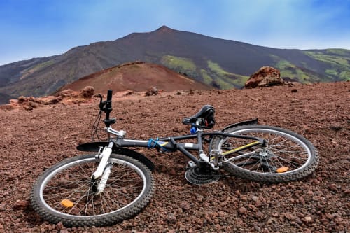 VTT posé sur le terrain volcanique près de l'Etna en Sicile avec des pentes verdoyantes