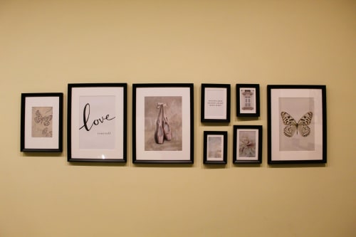 Parete galleria con stampe botaniche incorniciate, poster di balletto e opere d'arte con farfalle nella camera d'hotel contemporanea di Napoli