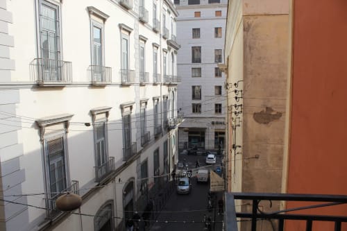 Vista di una stretta via napoletana dal balcone di BCH Toledo con edifici storici e traffico cittadino sottostante