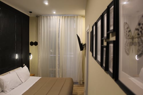 Camera moderna del Blackwoody Contemporary Hospitality a Napoli con letto queen, testata nera, tende trasparenti, quadri