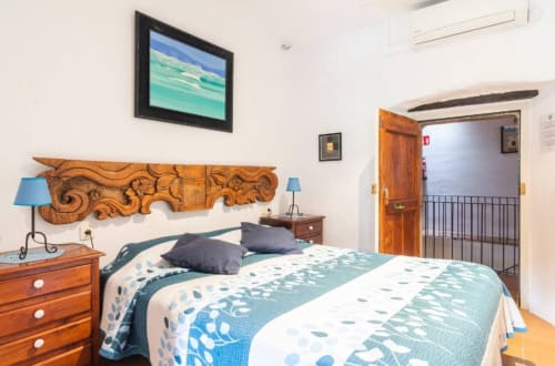 Dormitorio en Can Gat Vell en Girona con cabecero de madera, ropa de cama azul y comodidades modernas