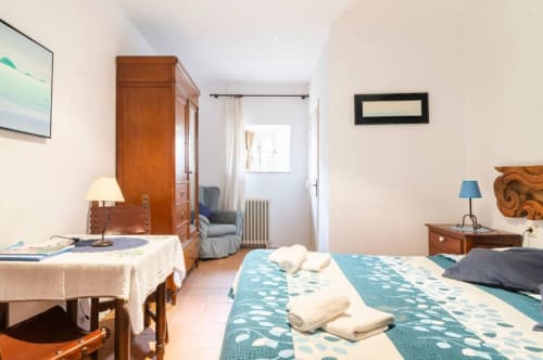 Habitación espaciosa en el B&B Can Gat Vell de Girona con ropa turquesa, muebles de madera y zona de lectura