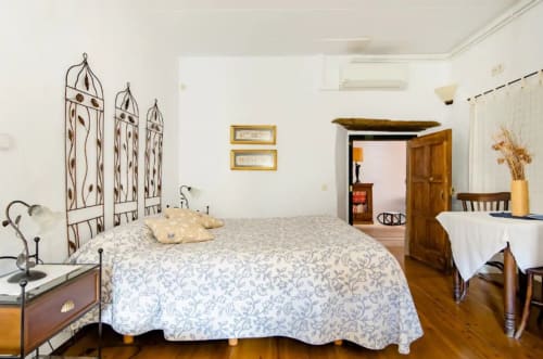 Amplia habitación en el Can Gat Vell B&B en Girona, con cabecero de metal ornamentado, colcha estampada, muebles de madera