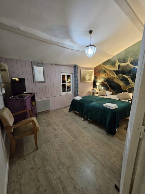 Geräumige Zimmer-Suite im Le Manoir Lacustre mit grünem Sammetbett, Fernseher, Sitzbereich und Gartenaussicht-Kunstwerk