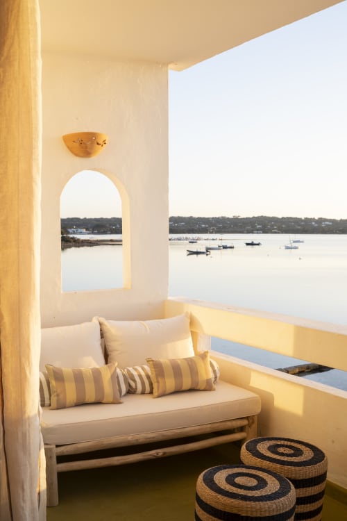 Rincón soleado en la costa con cama balinesa con vistas a los barcos del puerto de La Savina, Formentera