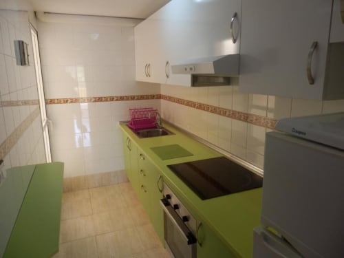 Cuisine galley lumineuse avec placards vert anis, cuisinière électrique et dosseret carrelé aux Apartamentos Taravilla, Puerto de