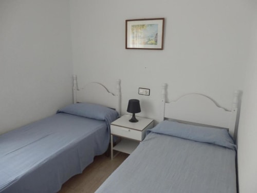 Chambre twin à Apartamentos Taravilla Puerto de Mazarrón avec lits bleus, têtes de lit blanches et lampe de chevet partagée