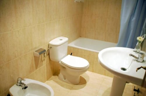 Salle de bains lumineuse aux Apartamentos Taravilla à Puerto de Mazarrón avec double vasque, toilettes et baignoire, carrelage beige