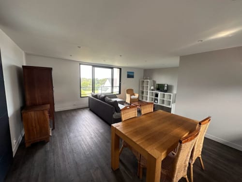 Séjour ouvert avec table à manger, canapé, rangements et vue sur mer à L'Écrin du Blanc Caillou, Saint Pair sur