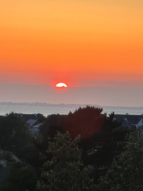 Coucher de soleil sur la mer à L'Écrin du Blanc Caillou, Saint Pair sur Mer, avec maisons côtières en silhouette