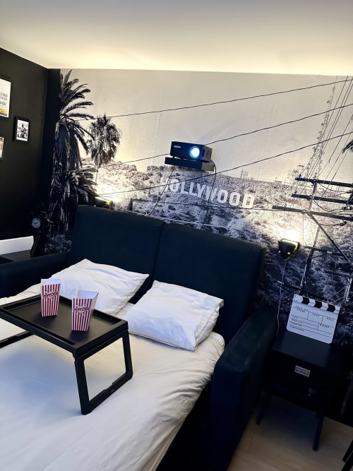 Cinema-themed studio apartment at Wellkhome Bordeaux with Hollywood sign mural, projector, popcorn setup, and white bedding