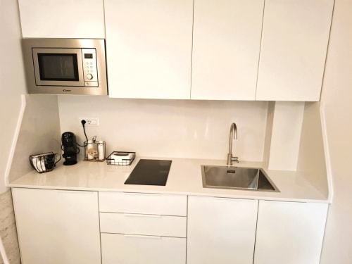 Cucina moderna bianca dell'appartamento Newhouse Bari con lavello in acciaio inossidabile, microonde e vista sulla città