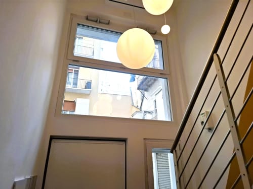 Ingresso moderno dell'appartamento a Bari con lampade a sospensione, alte finestre con vista sulla città e design minimalista all'hotel Newhouse