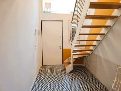 Ingresso con scale moderne all'appartamento Newhouse di Bari, con pavimento in mattonelle geometriche e gradini in legno