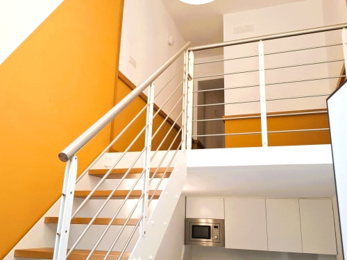 Moderna scala di hotel con ringhiera in metallo e parete accent arancione presso l'hotel Newhouse a Bari, Italia