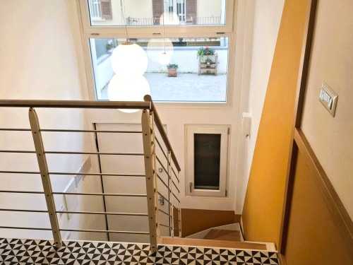 Scala moderna nell'appartamento Newhouse a Bari, con piastrelle geometriche e finestre con vista sulla città