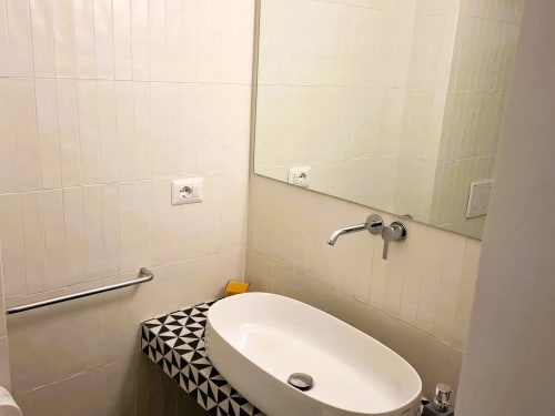 Lavabo moderno con specchio nell'appartamento Newhouse di Bari, Italia, con pareti rivestite in piastrelle e rubinetto a parete