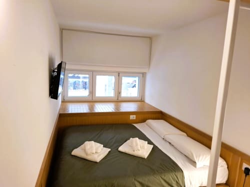 Accogliente camera da letto con vista sulla città, TV, rivestimenti in legno e letto con biancheria bianca presso Newhouse Bari