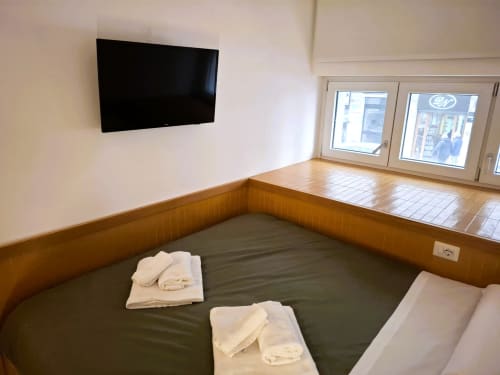 Moderno letto a Bari con TV a parete, rivestimento in legno, biancheria bianca e vista sulla città