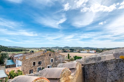 Édifice en pierre et murailles fortifiées dominant la campagne de Palafrugell sous un ciel bleu
