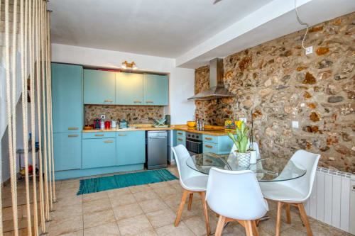 Cuisine turquoise moderne avec mur en pierre, table à manger et touches de bois chez Finques Garcia Enrich, Palafrugell