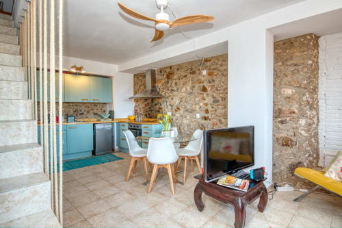 Cuisine ouverte et salle à manger modernes à Finques Garcia Enrich à Palafrugell avec mobilier turquoise et murs en pierre