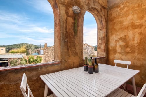 Terrasse de Finques Garcia Enrich à Palafrugell avec arches en pierre, table et chaises blanches surplombant le paysage
