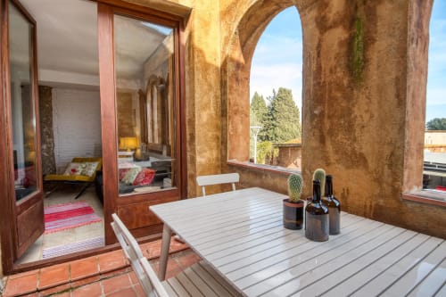 Terrasse rustique chez Finques Garcia Enrich à Palafrugell avec table en bois, chaises blanches, cactus et vue sur la campagne