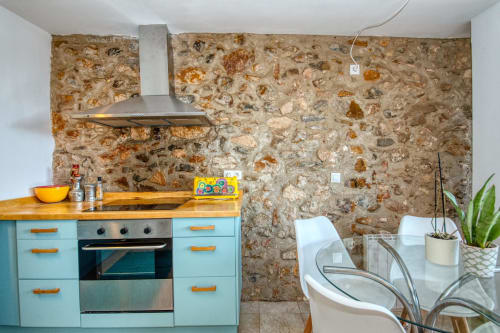 Cuisine moderne aux Finques Garcia Enrich, Palafrugell avec meubles turquoise, comptoirs en bois et crédence en pierre