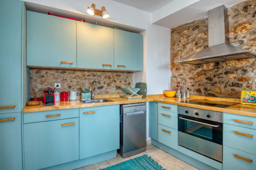Cuisine turquoise aux comptoirs en bois et murs en pierre chez Finques Garcia Enrich, Palafrugell