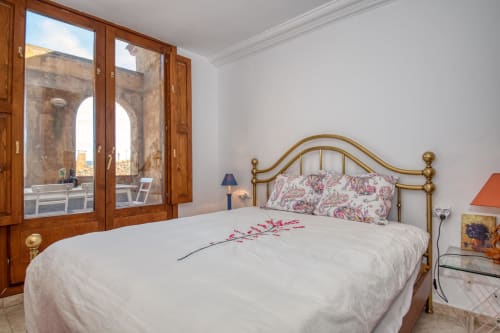 Chambre lumineuse aux Finques Garcia Enrich à Palafrugell avec lit en laiton, oreillers fleuris et portes terrasse