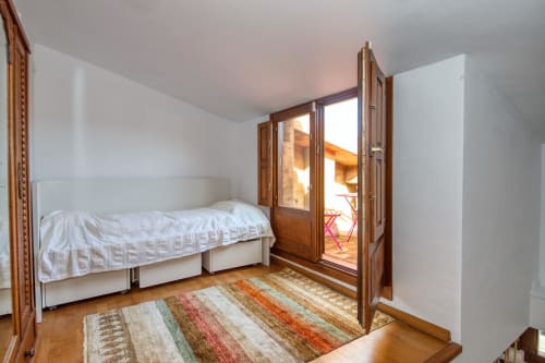 Chambre lumineuse à Finques Garcia Enrich à Palafrugell avec lit simple, portes en bois ouvrant sur terrasse et décor rayé coloré
