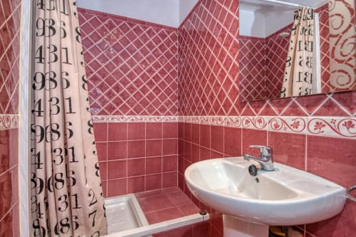 Salle de bain carrelée rouge et blanc avec lavabo et douche aux Finques Garcia Enrich, Palafrugell