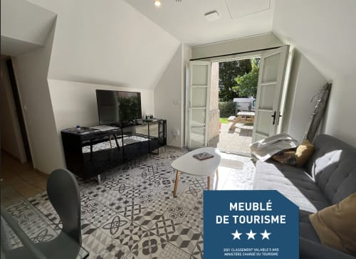 Landhaus Auguste Poulain in Blois: Wohnbereich mit Fernseher, Sofa, Türen zum Garten und gemustertem Boden