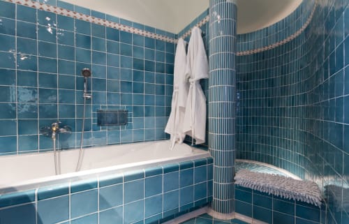 Salle de bain moderne avec carrelage bleu-vert, baignoire blanche, douche et serviettes à la Villa Marina Di Cavu à Bonifacio