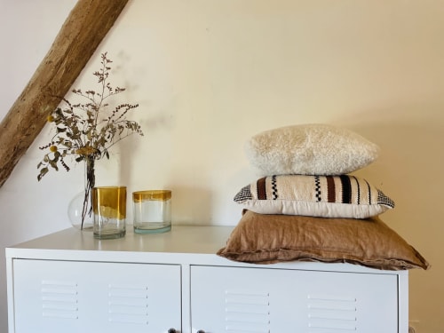 Étagère élégante décorée avec des coussins empilés, fleurs séchées en vase et bougies à la Maison Monsieur Léger, chambre d'hôtes à Montaut