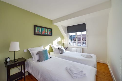 Bright bedroom with twin beds, lime green walls, and window view in Honfleur B&B